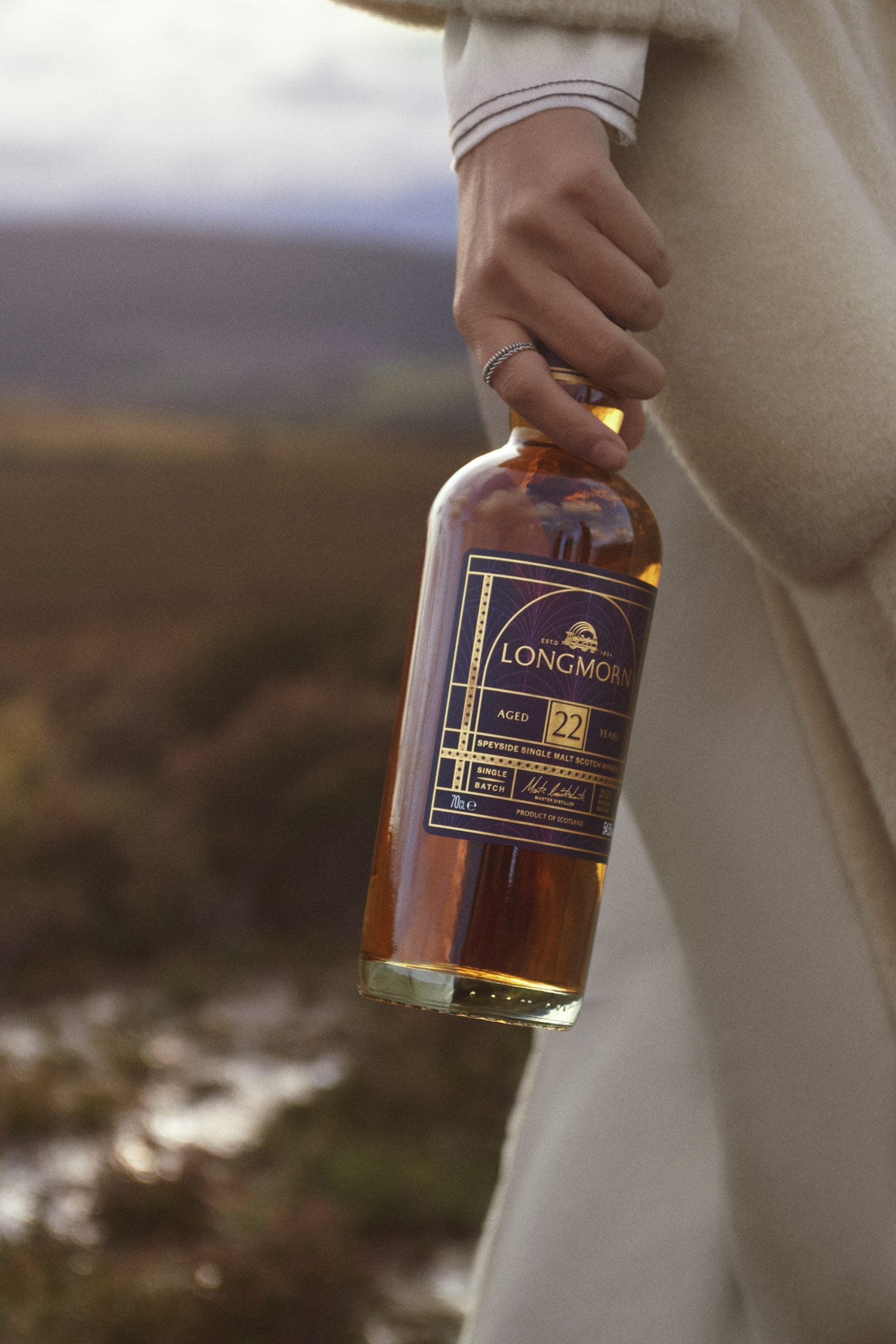 A womans hand holding a bottle of 22 Year Old Longmorn Whisky